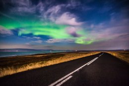 Северное сияние над дорогой в Исландии